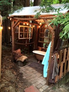 a bathtub in the middle of a wooded area with lights strung from it's roof