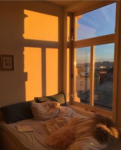 an unmade bed sitting in front of a window with the sun shining through it