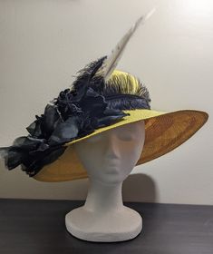 "Like all my hats and headpieces, \"Máxima\" is made from leftover millinery and/or craft supplies and materials. This hat is a basic wide brimmed hat made from genuine panama straw (handwoven in Ecuador) dyed to a lemon yellow color, but one part of the brim was a bit damaged when I found it; I trimmed it with a black lace & beaded hatband from another damaged hat, black flowers from 2 damaged fascinators, short black ostrich feathers, and a white feather. On the inside of the crown I sewed in a homemade fabric sweatband to make it sit more comfortably on the forehead, and the original tag remains in the back (from the company Scala). This hat will fit up to size 59 cm. (large) comfortably. The crown is 4.75 in./12 cm. tall, and the brim is 4.25 in./11 cm. wide. Despite having a lot on th Summer Ostrich Feather Mini Hats For Races, Summer Mini Hats With Ostrich Feathers For Races, Summer Races Mini Hat With Ostrich Feathers, Summer Race Day Mini Hats With Ostrich Feathers, Ostrich Feather Hats For Spring Races, Summer Hats With Ostrich Feathers For Races, Yellow Wide Brim Sun Hat For Kentucky Derby, Yellow Curved Brim Hat For Church, Yellow Hat With Curved Brim For Church