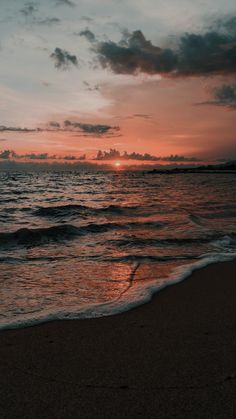 the sun is setting over the ocean with waves coming in to shore and some clouds