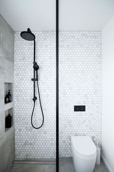 a white toilet sitting in a bathroom next to a shower head and hand held faucet