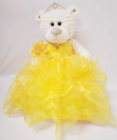 a white teddy bear wearing a yellow dress