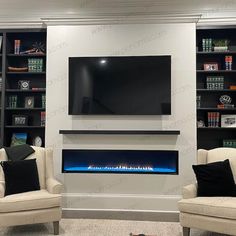 a living room with two chairs and a television mounted on the wall in front of it