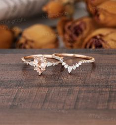 two gold rings with pear shaped diamonds sitting on top of a wooden table next to bananas