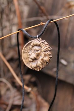 a necklace with a lion head hanging from it's side on a black cord