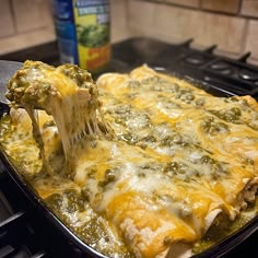 a casserole dish with spinach and cheese being lifted from the pan by a spatula