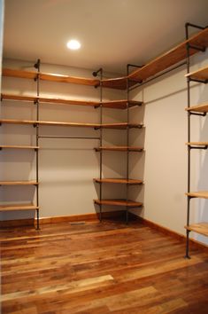 an empty walk in closet with wood floors and shelving units on the wall,