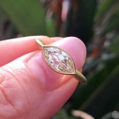 a person holding a ring with a diamond in it's center and gold band