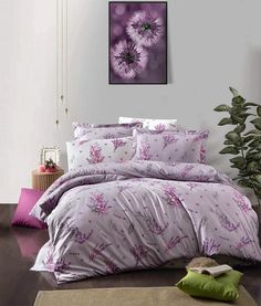 a bed with purple flowers on it in a room next to a potted plant