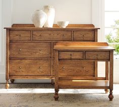 two white vases sit on top of a wooden dresser