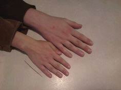 a person's hands resting on a table with their fingers touching the surface of the table