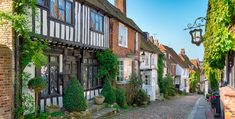 a cobblestone street lined with old buildings and ivy covered windows at sunset in england