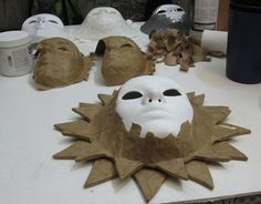 a white mask sitting on top of a table next to other masks and paper machs