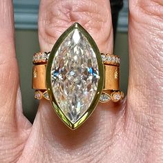 a woman's hand holding an engagement ring with a pear shaped diamond in the center