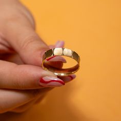 a woman's hand holding a gold wedding ring