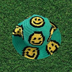 a crocheted hat with smiley faces on it sitting in the grass, top view