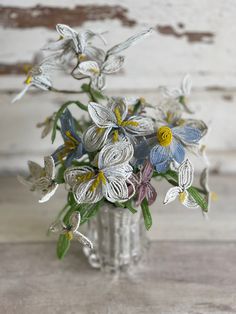 a glass vase filled with flowers on top of a wooden table