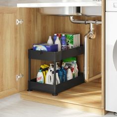 a kitchen cabinet with two bins filled with cleaning products next to a washer and dryer