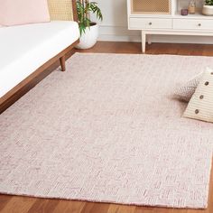 a living room area with white furniture and pink rug