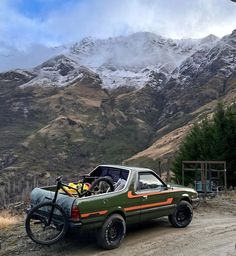 the truck is loaded with bicycles and gear on it's flatbed in front of snowy mountains