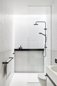 a white tiled bathroom with black accents