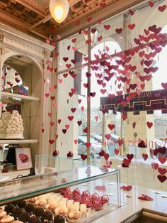 a display case filled with lots of different types of cakes and cupcakes in front of a window