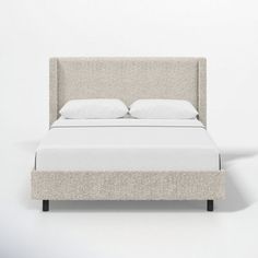 a bed with white sheets and pillows on it