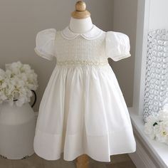 This Ivory Smocked Baby Girl's Heirloom Dress Is Precious!! Done By Feltman Brothers (Fine Children's Apparel), This Little Dress Has Details Galore!! This Color Combination Is No Longer In Production Making It A Sweet Rare Find! The Entire Bodice Is Smocked And Has A Lattice Design Embroidery Done In A Pale Butter Yellow Threading. Just Above The Gathers Of The Waist Is An Embroidered Chevron Border. Just Above That Is A Gorgeous Hand-Embroidered Garland Of Yellow And White Floral Wreaths With Fitted Cream Smocked Dress With Smocked Cuffs, Embroidered Garland, Feltman Brothers, Heirloom Portraits, Heirloom Dresses, Floral Wreaths, Butter Yellow, Lattice Design, Cream Yellow