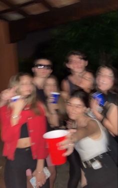 a group of people standing next to each other holding onto red cups in their hands