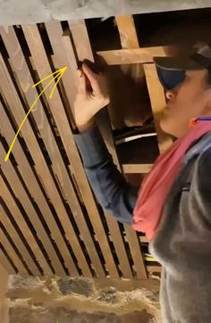 a man is working on the ceiling in his house with wood slats behind him