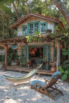 a hammock and chair in front of a small wooden house with green shutters