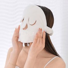 a woman covering her face with a white sheet while wearing a sleep mask on her head