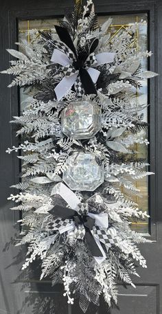 a white christmas tree decorated with black and silver ribbons, bows and snowflakes