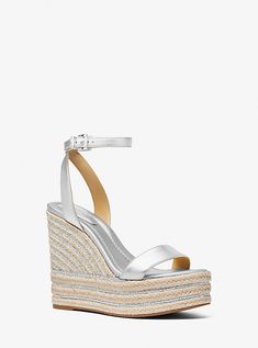 Greet the sun glamorously in the Leighton wedge sandal. The metallic straps are set on a sky-high, jute-trimmed wedge sole with metallic striping. The platform wedge delivers height without sacrificing wearability. Style them with everything from a flirty sundress to a luxe pool cover-up. Silver Wedge Sandals For Summer, Michael Kors Platform Wedge Sandals For Summer, Michael Kors Summer Party Heels, Michael Kors Platform Wedge Sandals For Beach, Michael Kors Wedge Heel Sandals For Summer, Michael Kors Wedge Heel Sandals For Spring, Michael Kors High Heel Platform Wedge Sandals, Michael Kors Open Toe Wedge Sandals For Summer, Michael Kors Open Toe Wedge Sandals For Spring