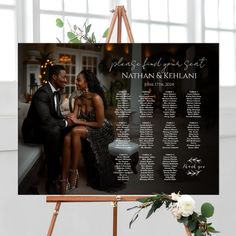 a couple sitting on a bench in front of a black and white wedding seating chart