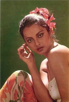 a woman with a flower in her hair is sitting on the ground and looking at the camera