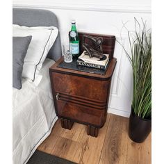 a bedside table with a bottle of water and books on it next to a bed