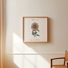 a chair sitting in front of a wall with a framed sunflower on it's side