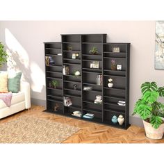 a living room filled with lots of black shelves next to a white couch and potted plant