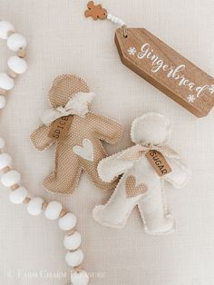 two small teddy bears are next to a wooden sign and bead necklace on a white surface