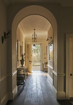 an archway leading to a hallway with chairs and vases on the table in front of it