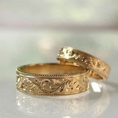 two gold wedding rings sitting next to each other