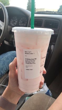 a person holding up a pink drink in their hand