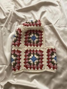 a crocheted dishcloth on a bed with white sheets and red, white, and blue squares