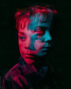 a young boy with red and blue lights on his face, looking at the camera