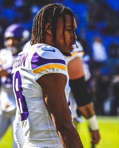 a football player with dreadlocks standing on the field