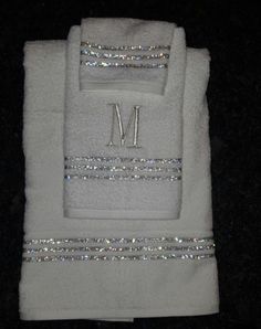 two white towels with silver sequins and the letter m on them are folded up