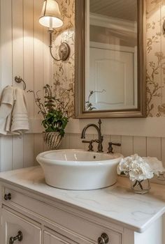 a bathroom sink sitting under a mirror next to a white counter top with flowers on it