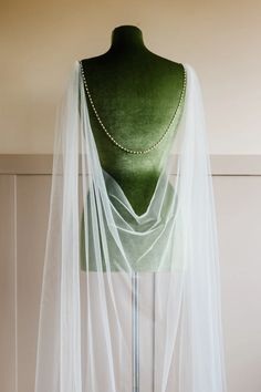 a green mannequin with a white veil draped over it