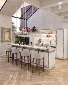 a kitchen with an island, bar and stools next to it in front of a large window